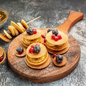 Stuffy pancakes with lemons on cutting board and honey on the left side of the gray table top view