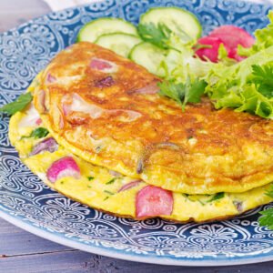 Breakfast. Omelette with radish, red onion and fresh salad on blue plate. Frittata - italian omelet.